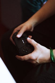 Close-up shot of hands playing with a game controller indoors, showcasing gaming enthusiasm.